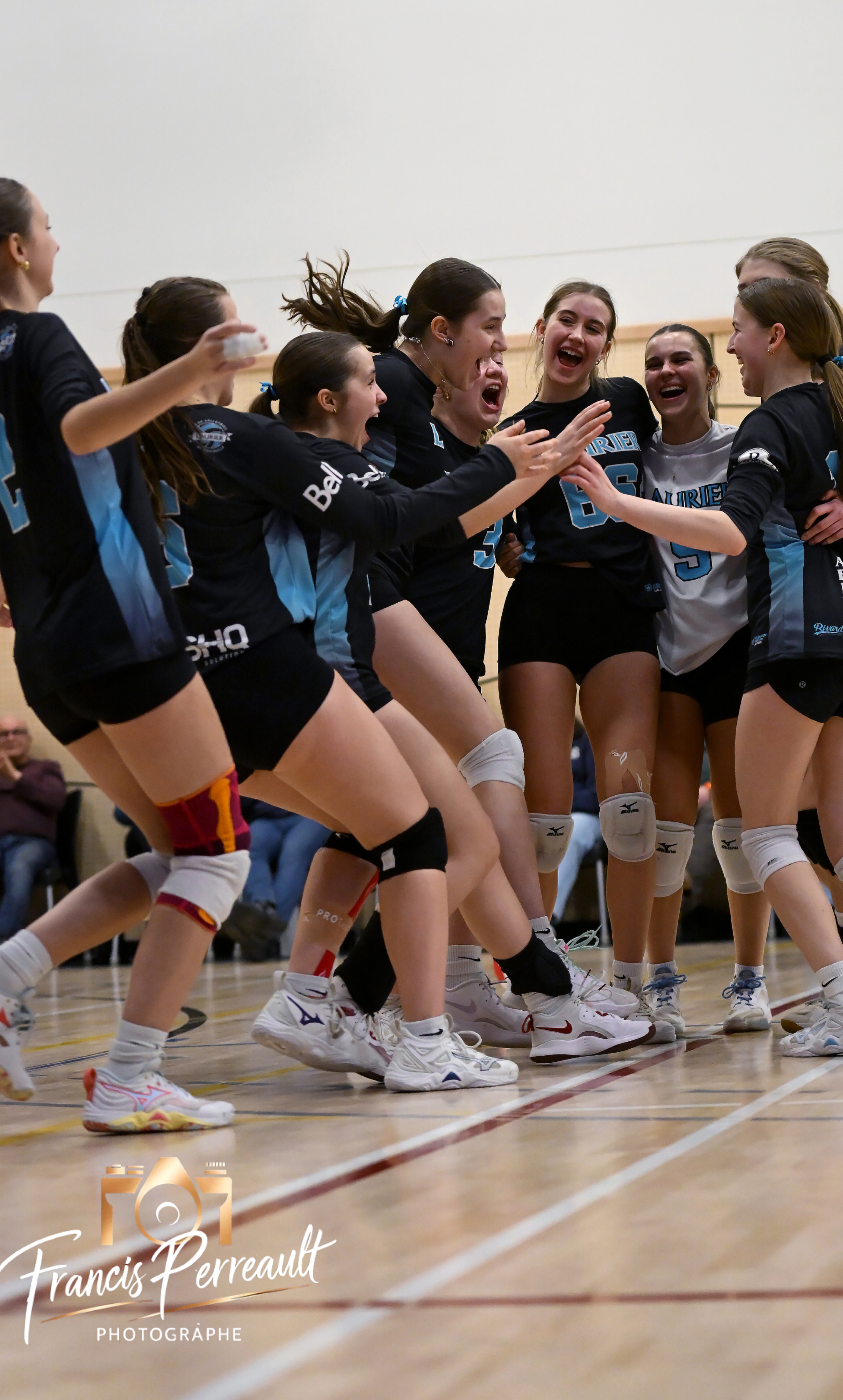 Joueuses du Club de volleyball Laurier qui célèbrent ensemble sur le terrain, souriantes et énergiques.