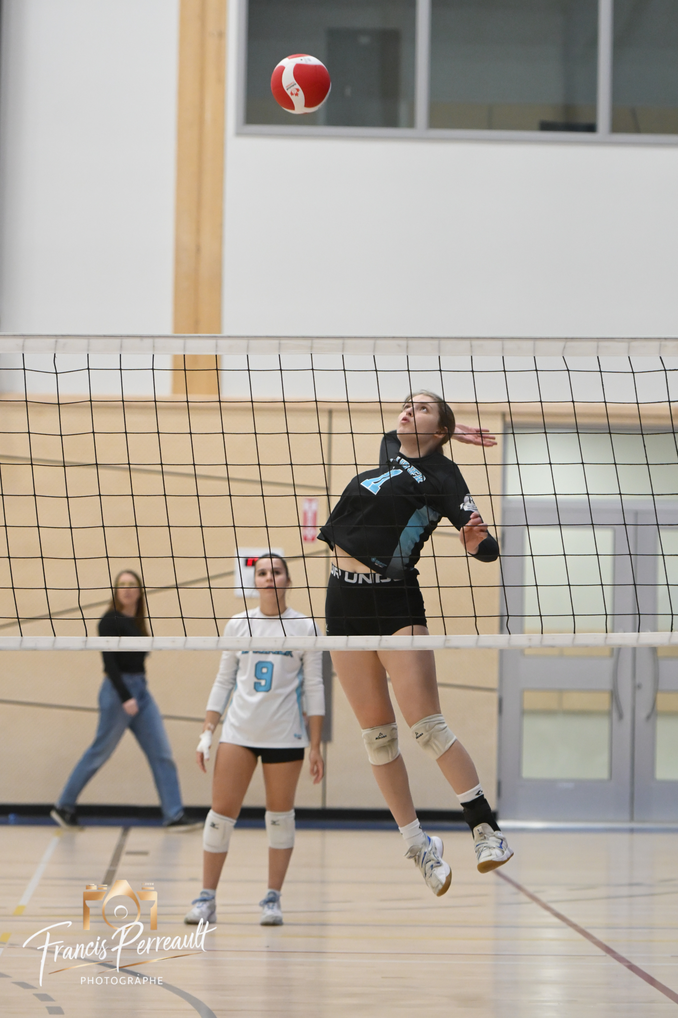 Joueuse du Club Laurier qui saute pour frapper le ballon au filet lors d'un match de volleyball intérieur.